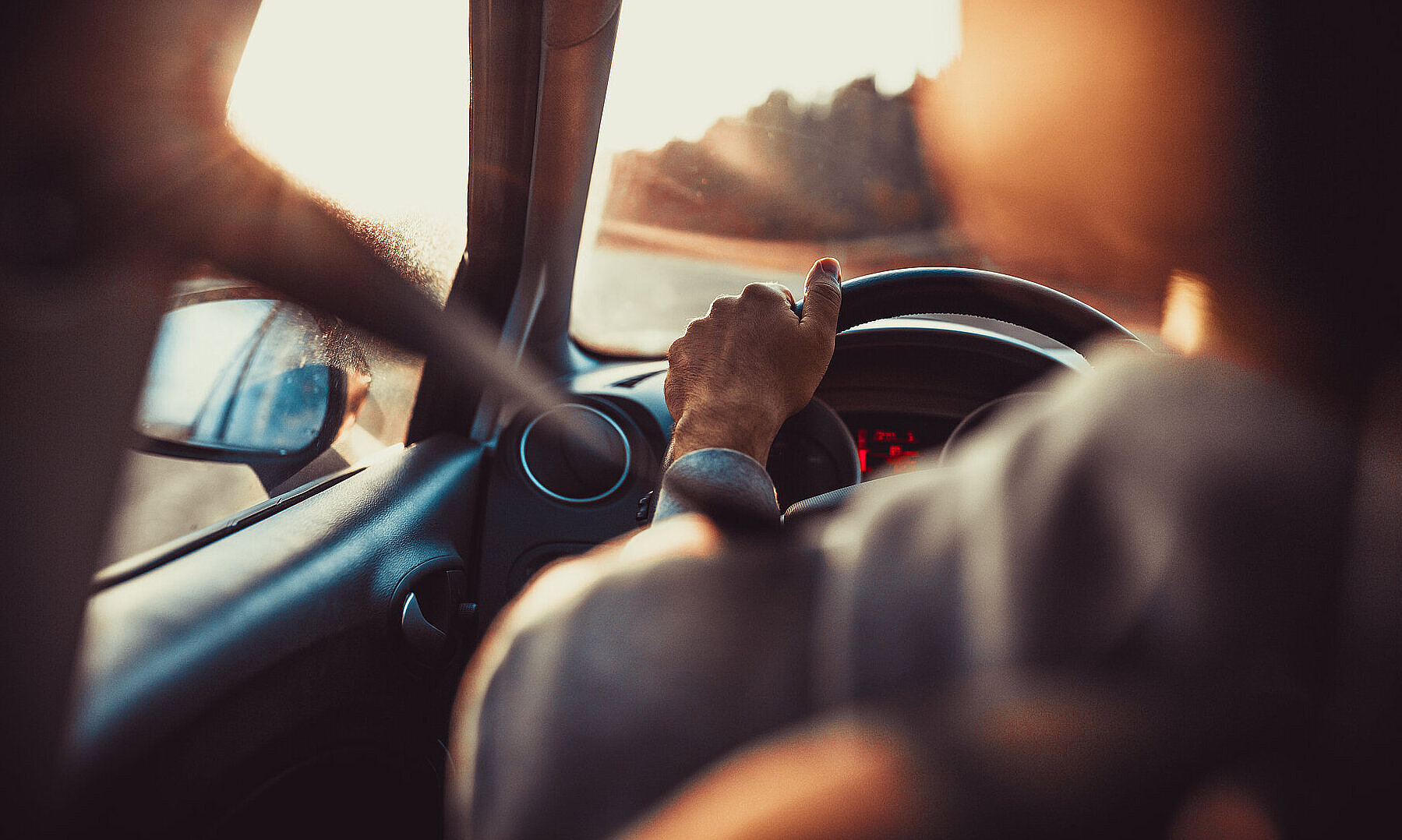 Man driving car, hand on steering wheel, looking at the road ahe