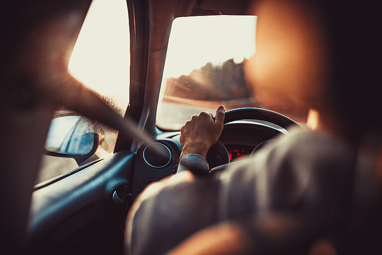 Man driving car, hand on steering wheel, looking at the road ahe
